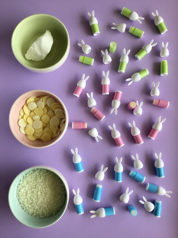 shea butter, cocoa butter and bees wax in three separate bowls surrounded by green, pink and blue mini bunny lip balm tubes