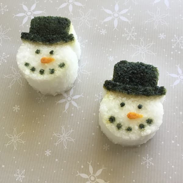 two epsom salt cakes in the shape of a snowman's face with the details painted with food coloring