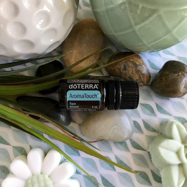 a bottle of doterra aromatouch essential oil surrounded by river rocks and grasses