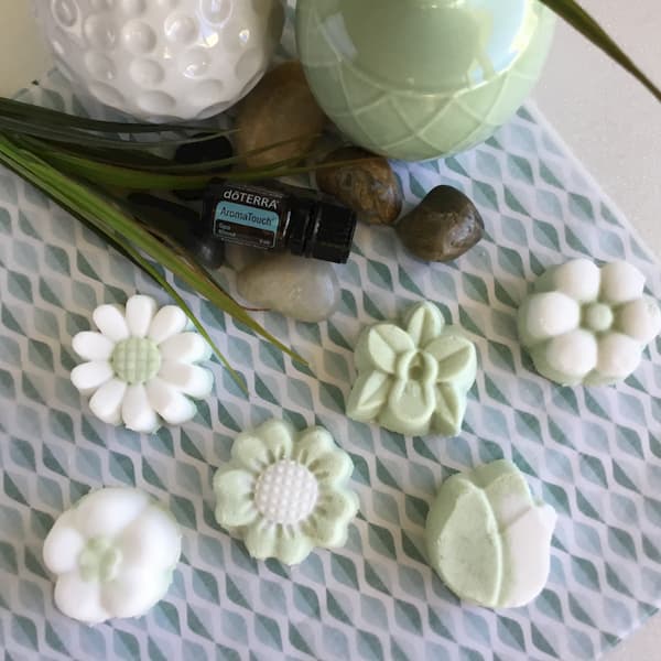 six green and white bath bomb flowers with a bottle of doterra aromatouch essential oil