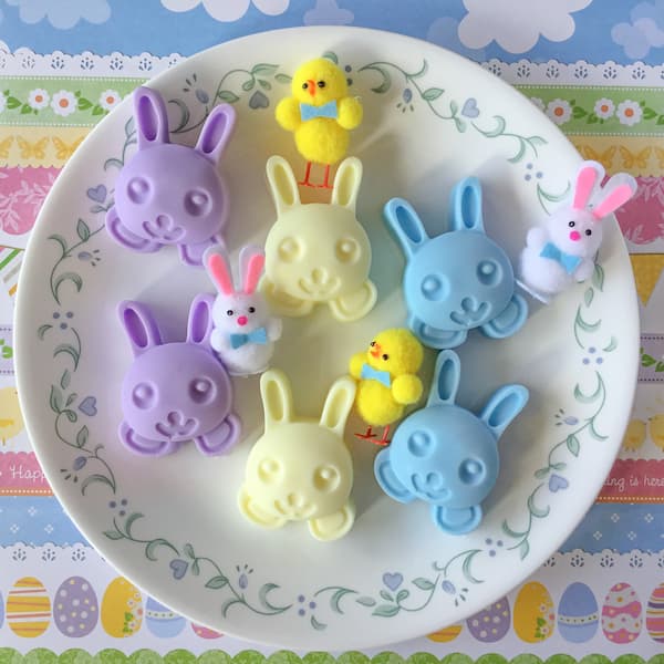 purple, yellow and blue bunny soaps sitting on a round white plate