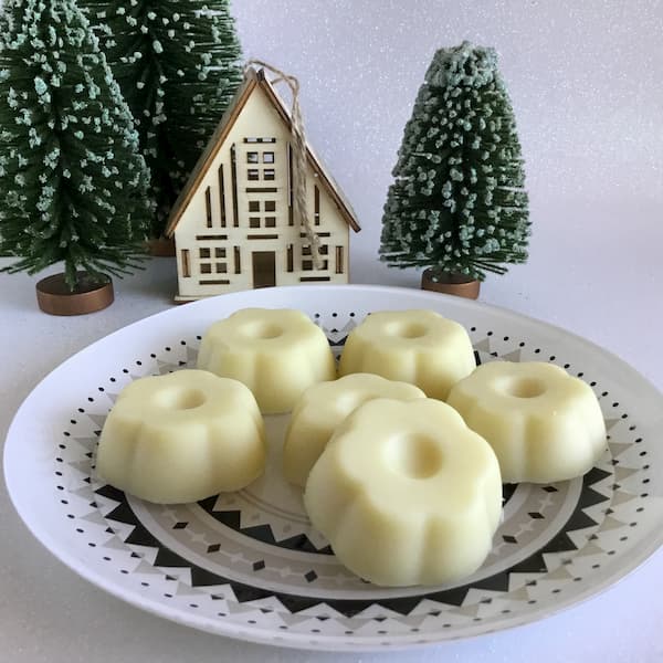 six flower-shaped essential oil lotion bars sitting on a plate with scandinavian decorations in the background
