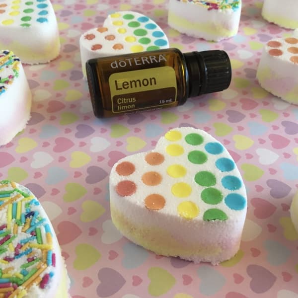 bottle of doterra lemon essential oil behind heart-shaped bath bomb decorated with cake sprinkles