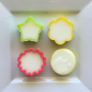 four recently poured essential oil lotion bars in four floral molds laid out on a square plate to set
