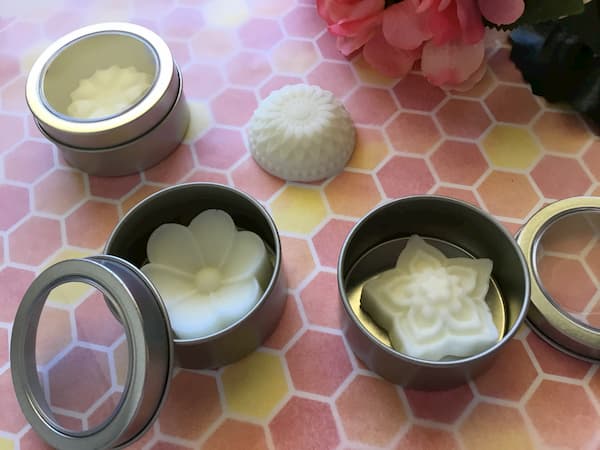 floral essential oil lotion bars inside round metal canisters