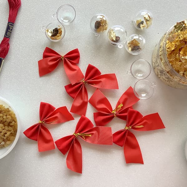 6 small red velvet christmas bows scattered on a white glittery surface